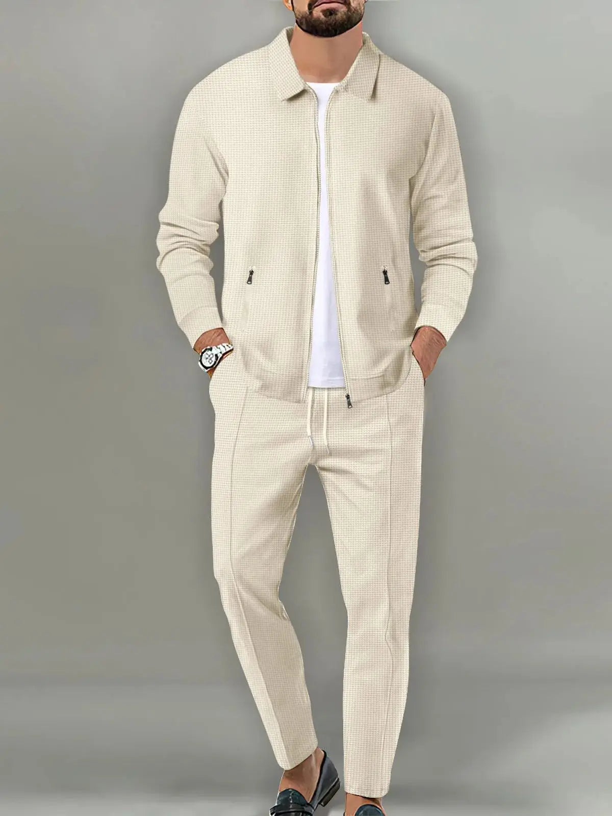 Man wearing a beige tracksuit against a gray background