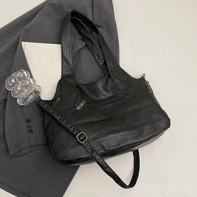 Black leather bag with a glass and book on a gray suit jacket