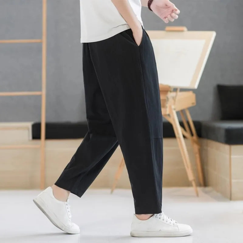 Person wearing black pants and white sneakers in a minimal indoor setting