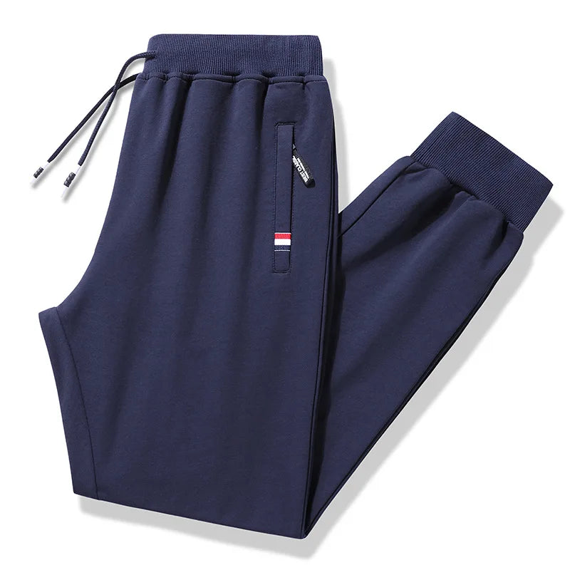 Navy blue jogger pants with a small flag patch on a white background