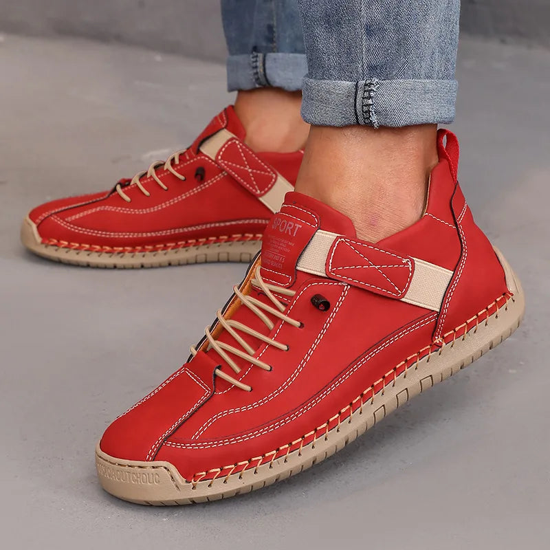 Red sneakers with beige accents worn by a person on a gray surface