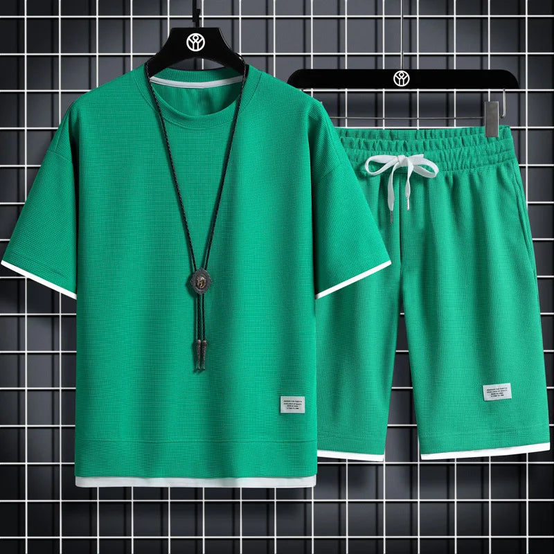 Green t-shirt and shorts set on hangers against a black grid background