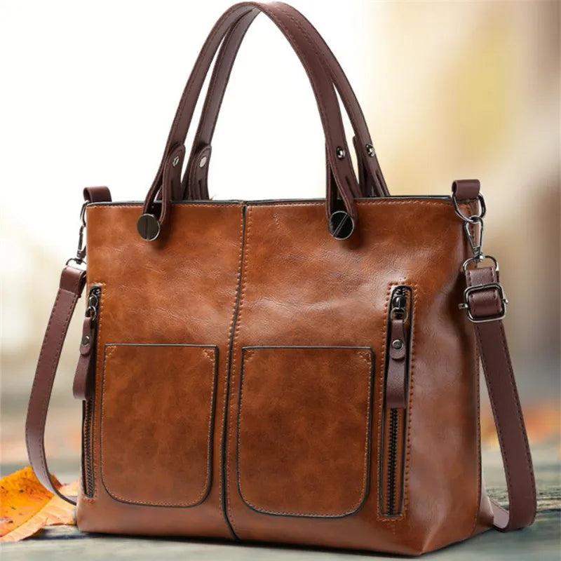 Brown leather handbag with a shoulder strap on a blurred background