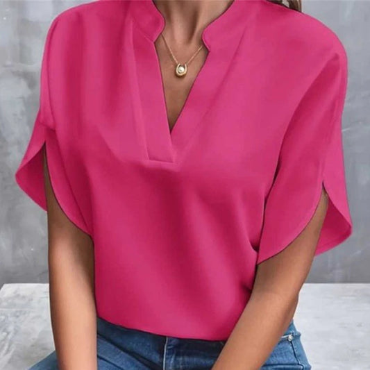 Person wearing a bright pink blouse with a gray background