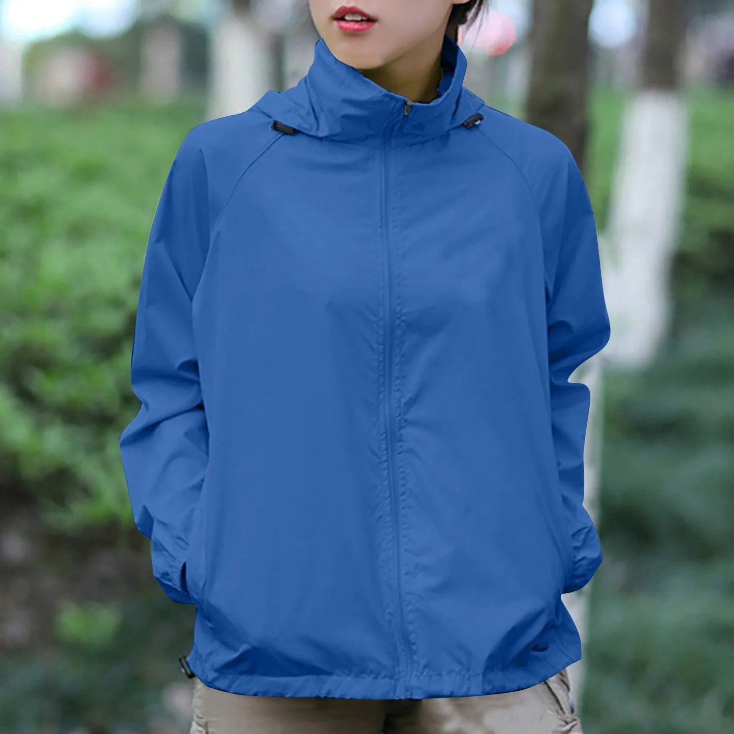 Person wearing a blue jacket outdoors with a blurred green background