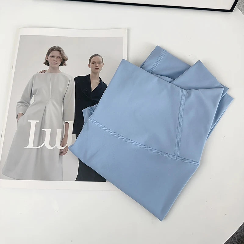 Folded blue fabric on a white surface with a magazine featuring two models.