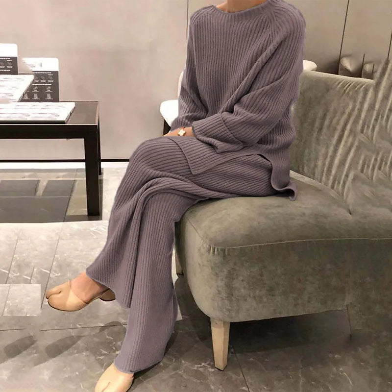 Person wearing a purple knit outfit sitting on a gray chair in a modern room.