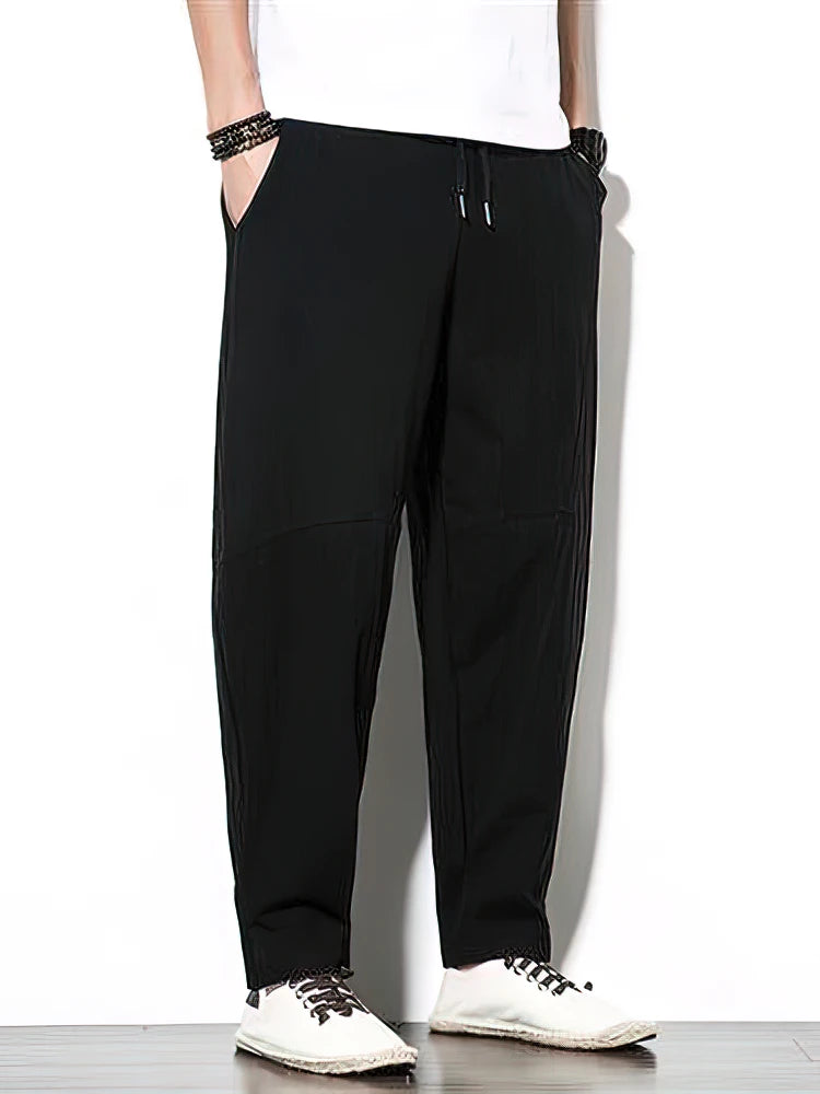 Person wearing black pants and white sneakers on a white background