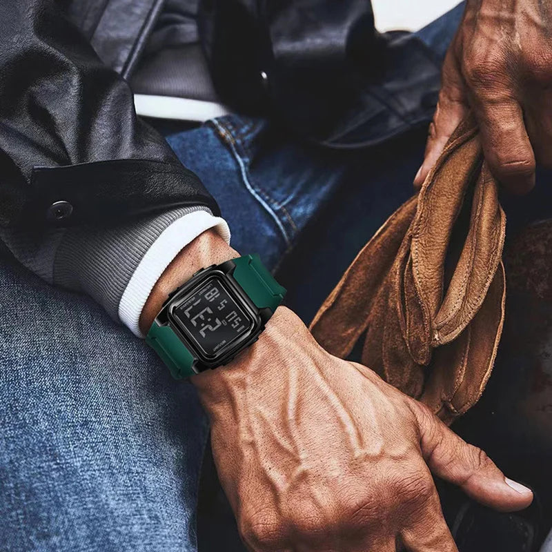 Person wearing a digital watch with a green strap, holding a brown leather glove.