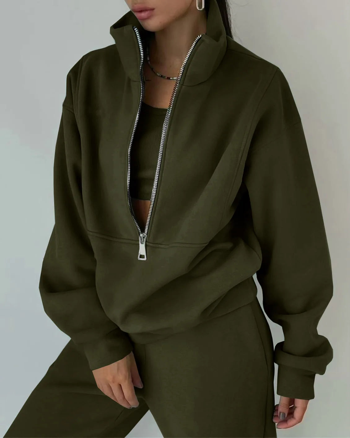 Person wearing a green zip-up hoodie and pants against a neutral background