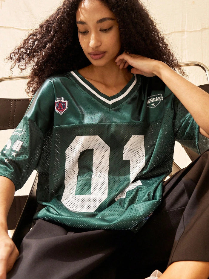A woman wearing a black V-neck sports jersey with the number '01' on it. The jersey has white text and trim, and it appears to be made of polyester fabric.