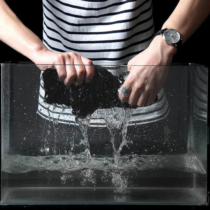 Person washing a black shoe under running water in a sink.