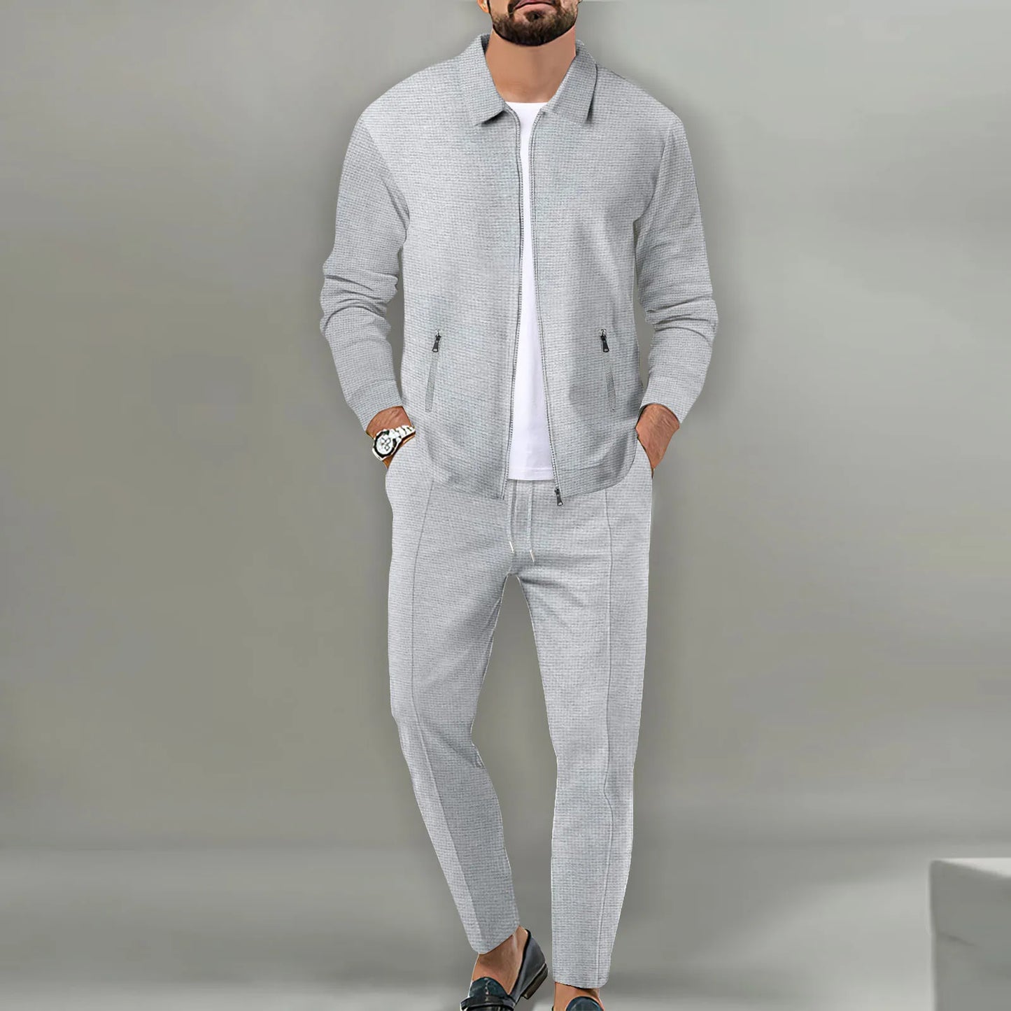 Man wearing a gray tracksuit against a plain background