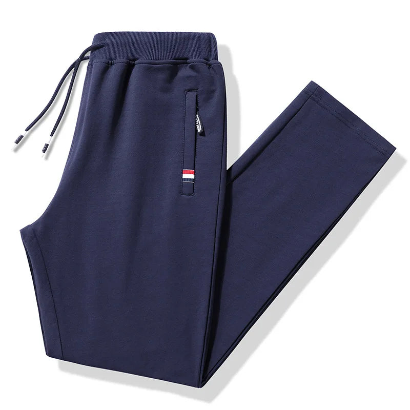 Navy blue jogger pants with a small flag patch on a white background