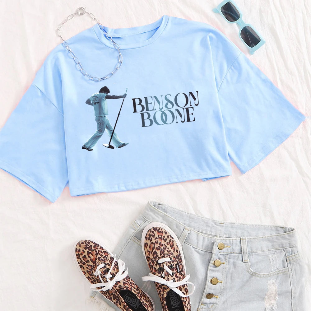 Light blue t-shirt with 'Benson Boone' graphic, leopard print shoes, sunglasses, and denim shorts on a white background