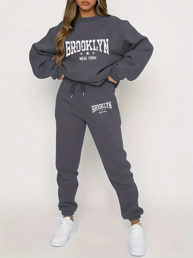 Person wearing a gray 'Brooklyn New York' sweatshirt and jogger set on a white background