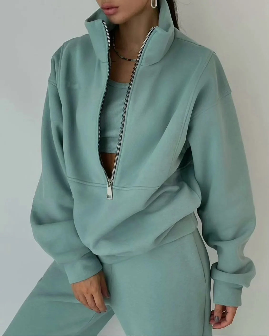 Person wearing a light blue tracksuit against a plain background