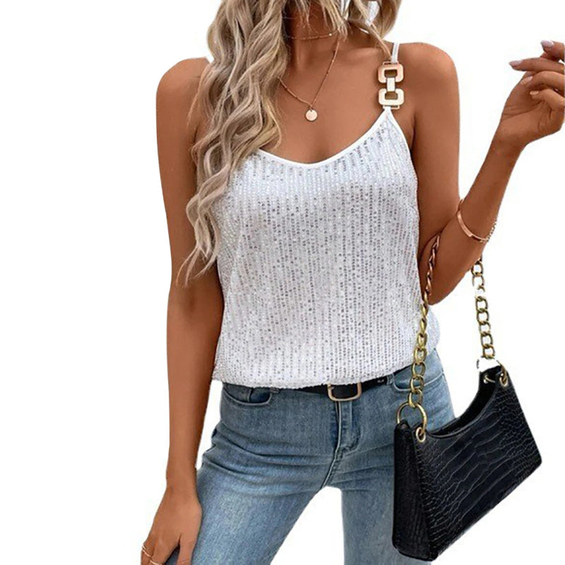 Woman wearing a white sequin tank top and blue jeans, holding a black handbag.