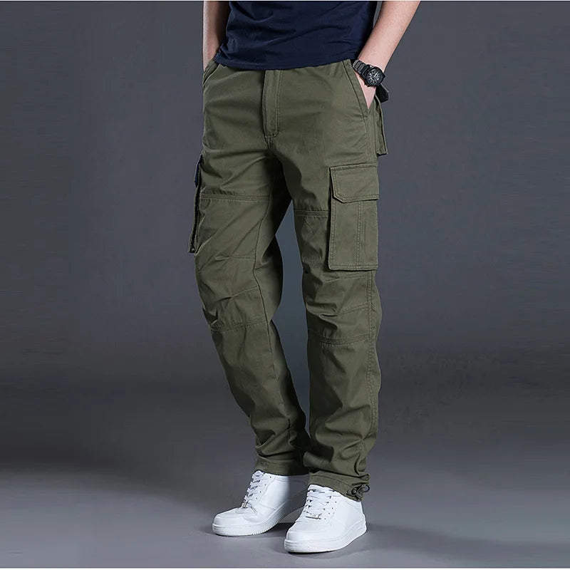 Person wearing olive green cargo pants on a gray background