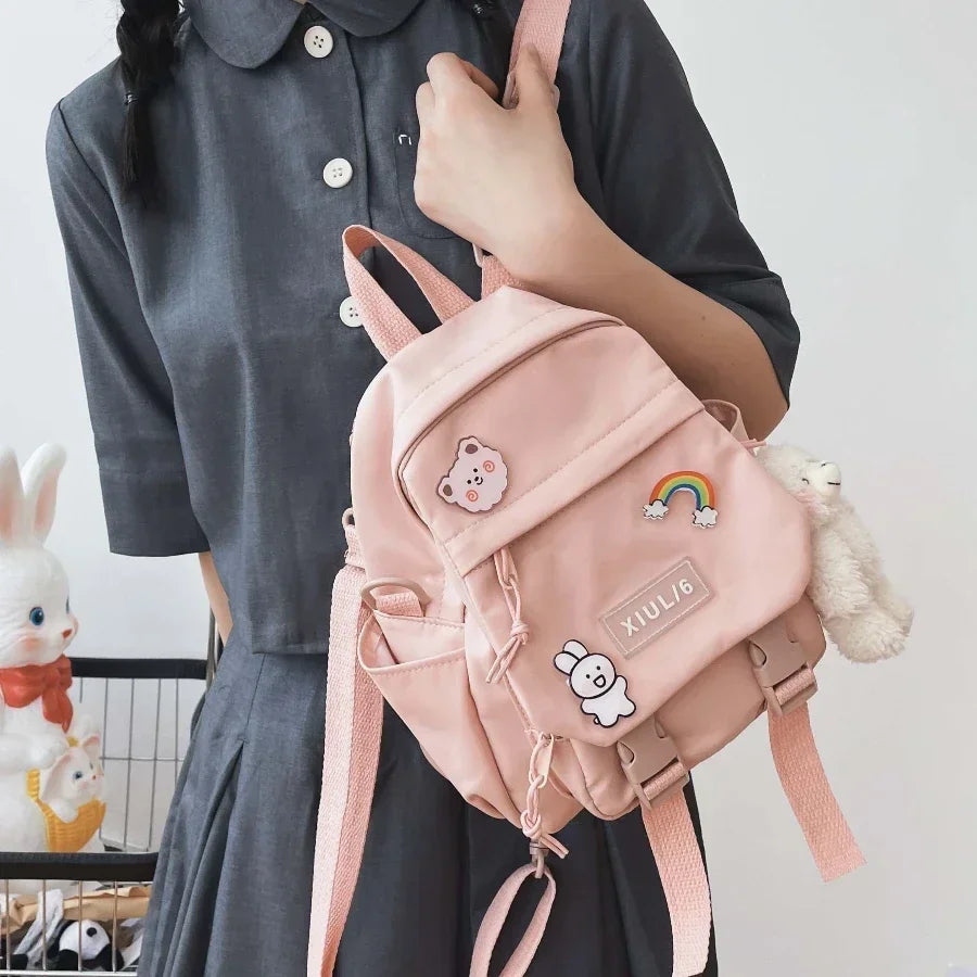 Person holding a pink backpack with decorative elements against a neutral background
