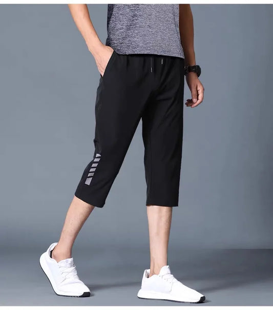 Person wearing black athletic pants with a gray background