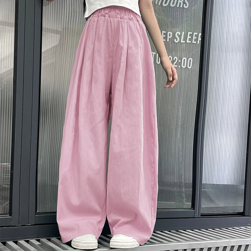 Person wearing pink wide-leg pants standing in front of a glass door.