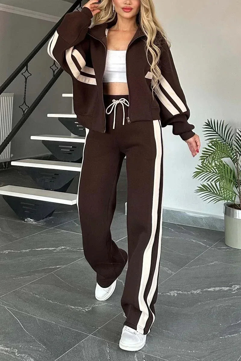 Woman wearing a brown tracksuit with white stripes in a home setting.
