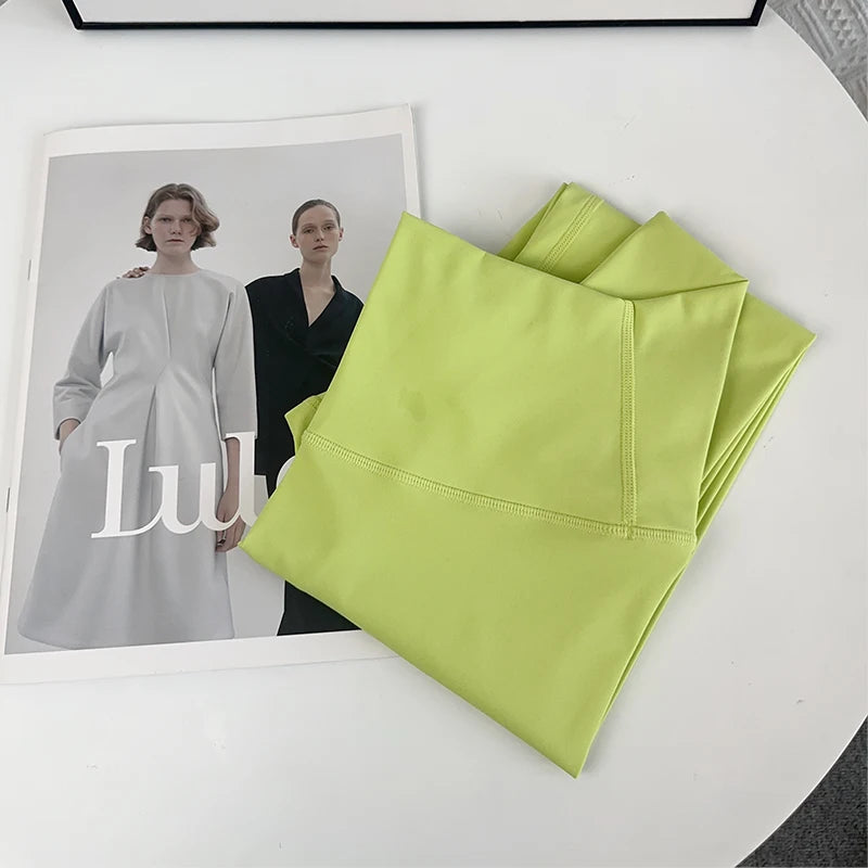 Folded green fabric next to a magazine with a fashion model on a white surface