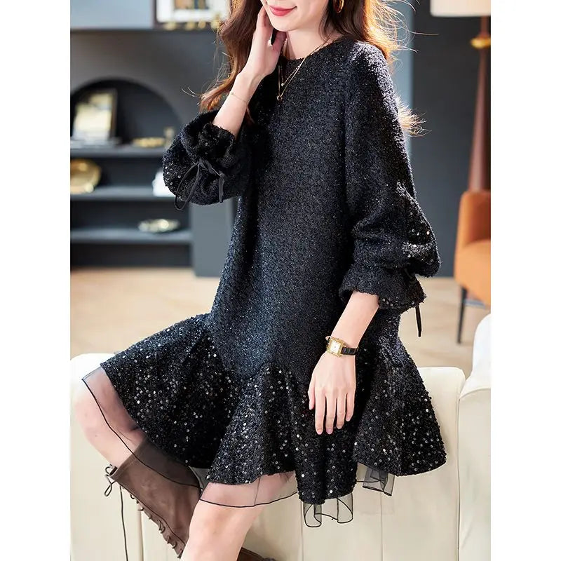 Woman wearing a black sequin dress sitting on a couch in a room.