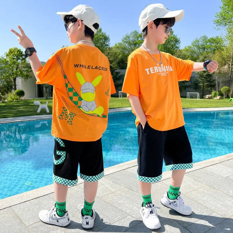 Two children wearing orange t-shirts by a poolside with trees in the background