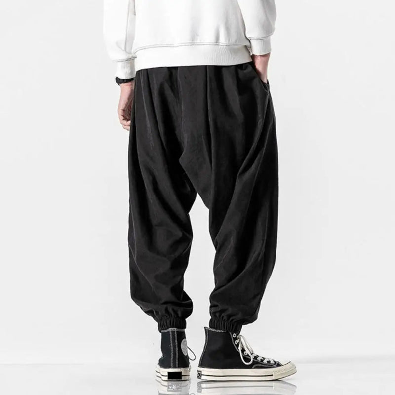 Person wearing black baggy pants and black high-top sneakers on a white background