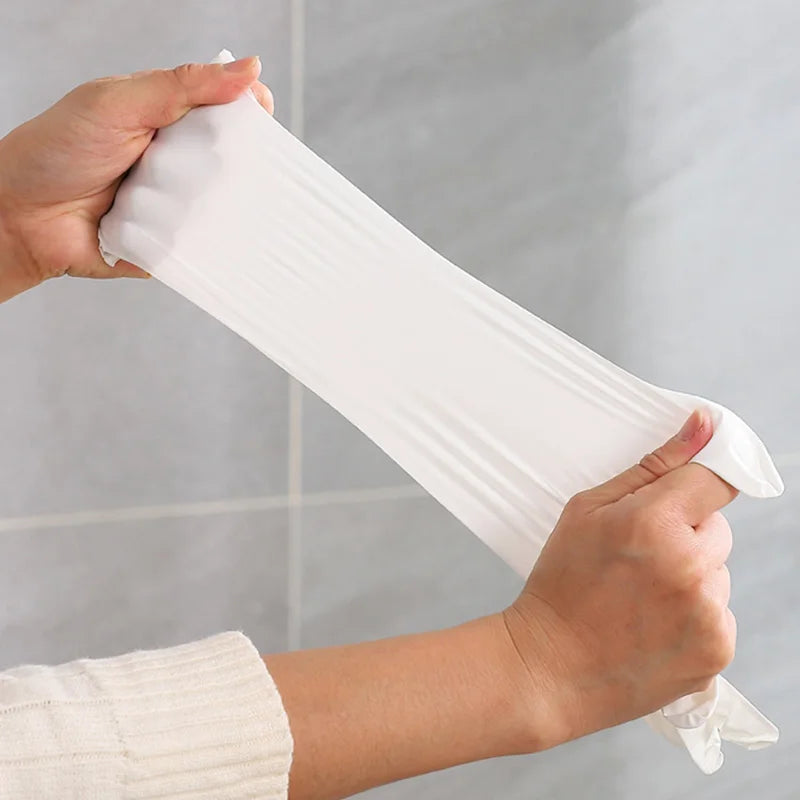 Person holding a white silicone sleeve against a gray tiled wall.