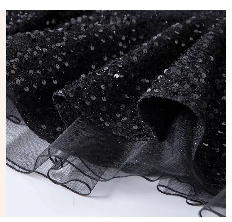Black sequin fabric with sheer overlay on a white background