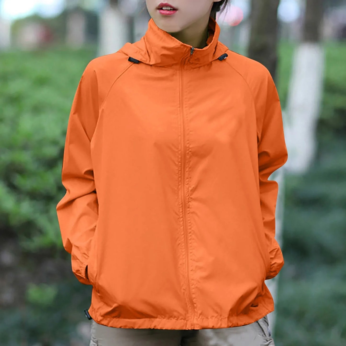 Person wearing an orange jacket outdoors with a blurred green background