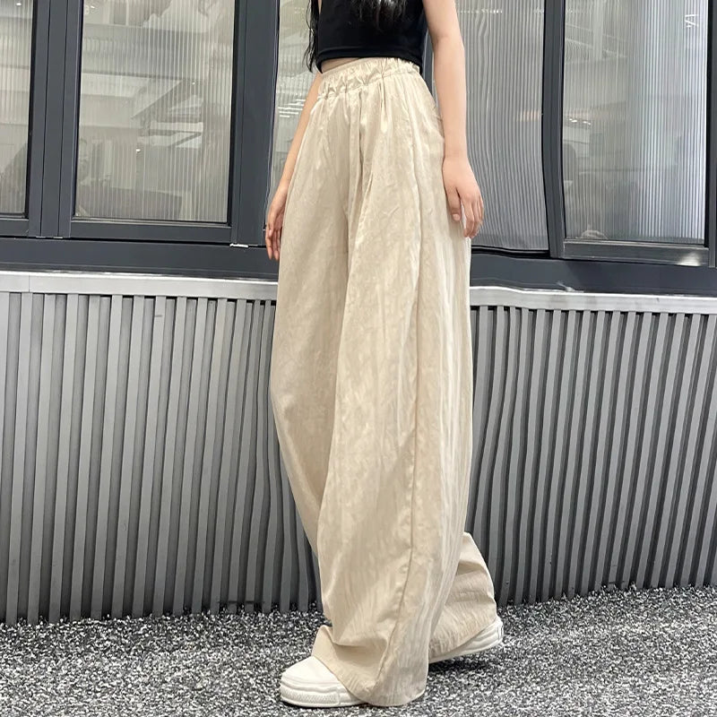 Person wearing beige wide-leg pants and a black top in front of a window.