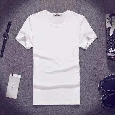 White t-shirt on a gray surface with a phone, watch, and bottle in the background