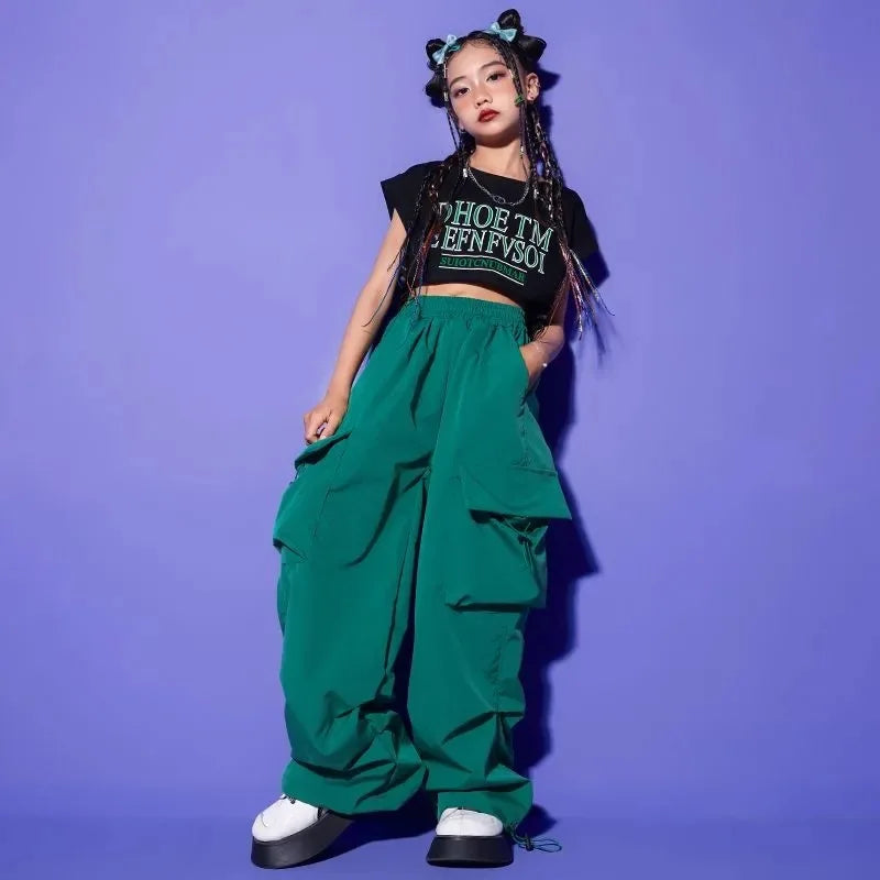 Person wearing a black crop top with text and green baggy pants against a purple background