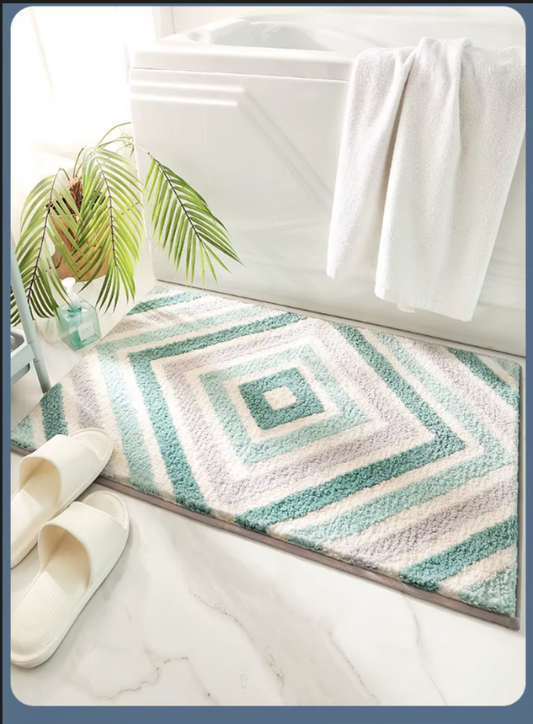Patterned bath mat on a bathroom floor with towels and slippers.