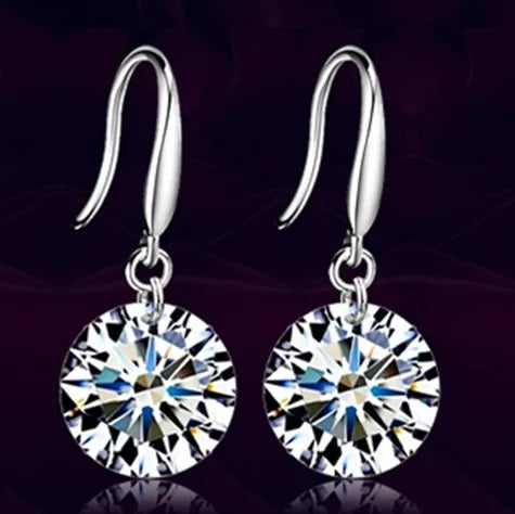 Silver earrings with large round gemstones on a dark background