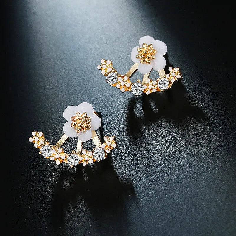 Pair of floral earrings with gold and crystal details on a dark background