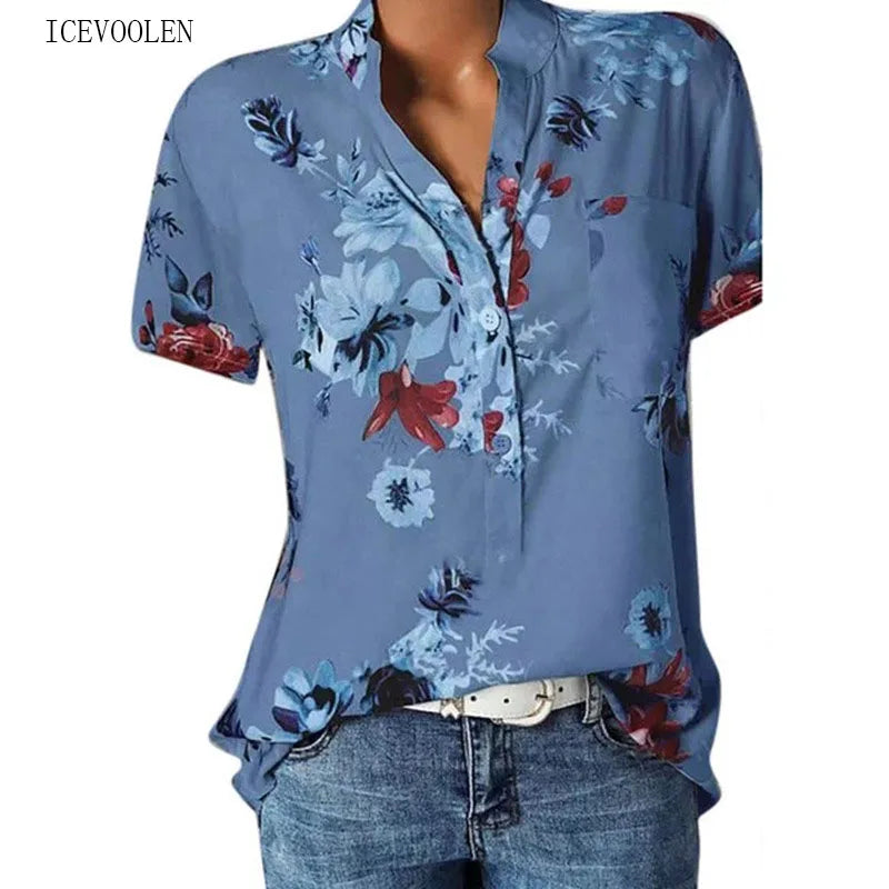 Blue floral blouse with red accents worn by a person on a white background