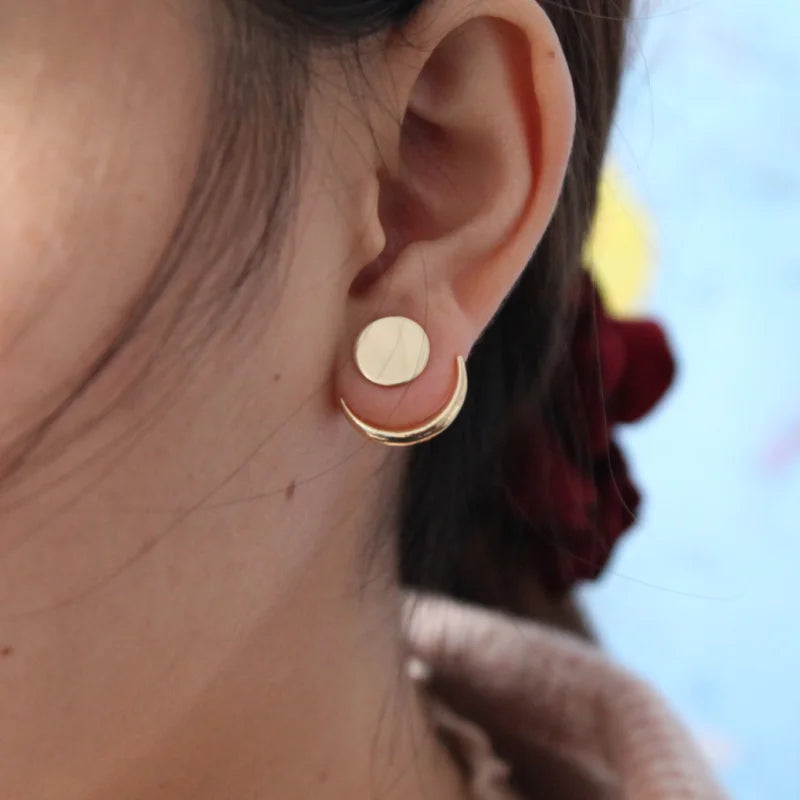 Close-up of a person wearing gold earrings with a blurred background