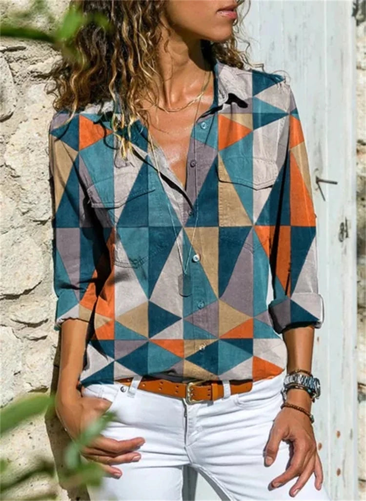 Person wearing a colorful geometric patterned shirt against a stone wall.