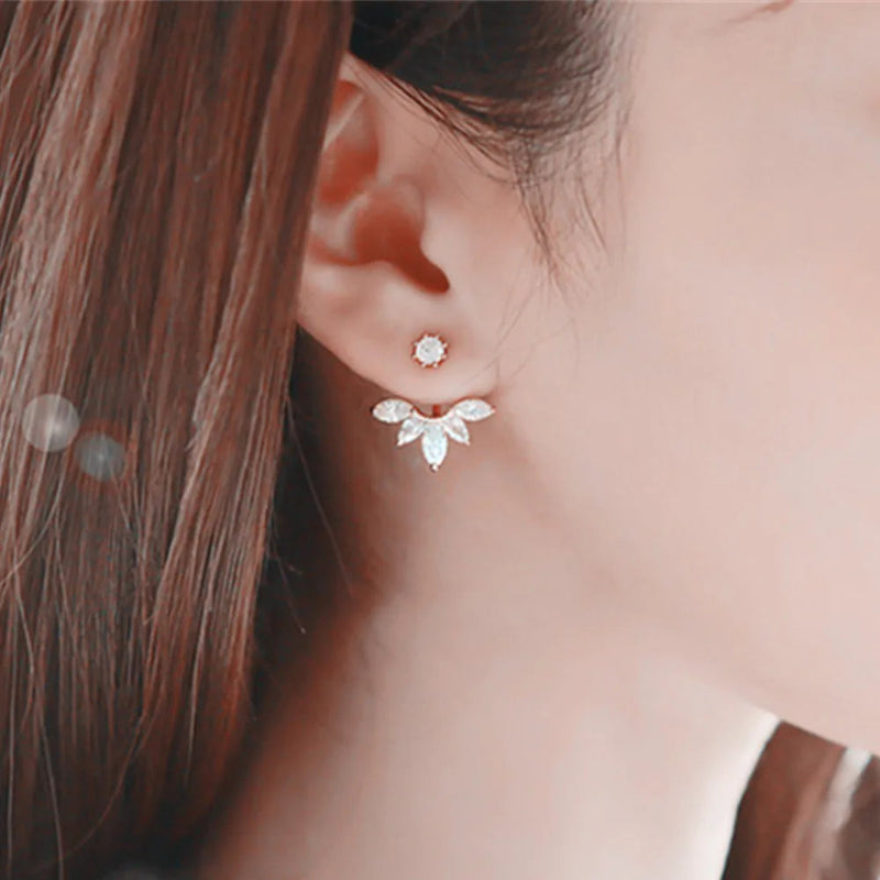 Close-up of a person wearing a silver butterfly earring with a clear gemstone.