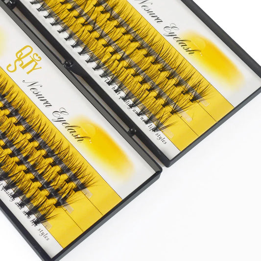 Eyelash extensions in open boxes with yellow and white labels on a white background