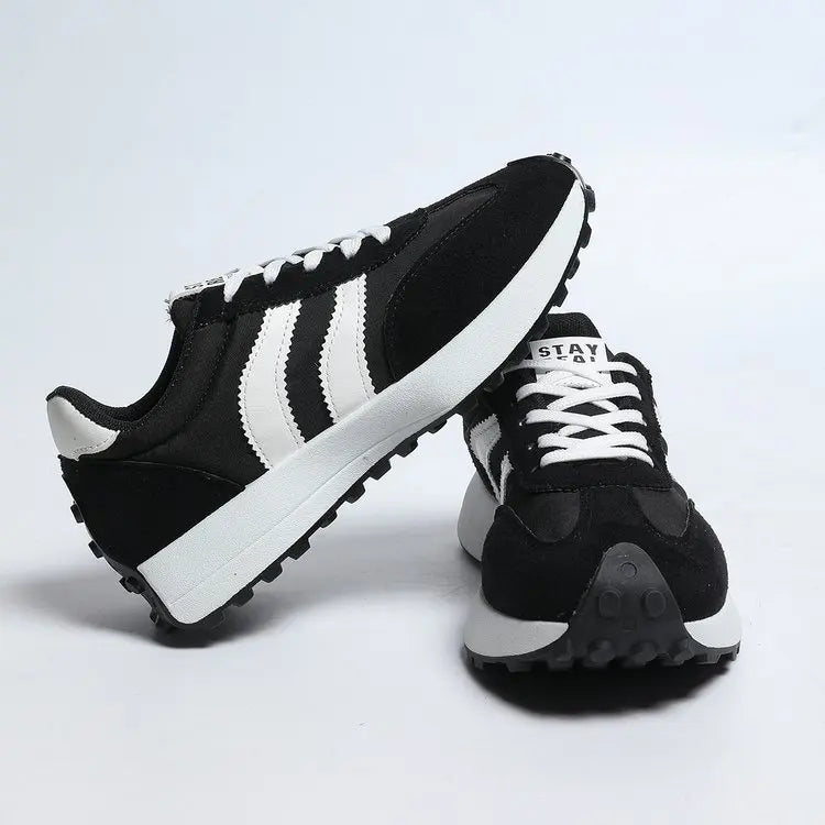 Black and white sneakers with Adidas logo on a light gray background