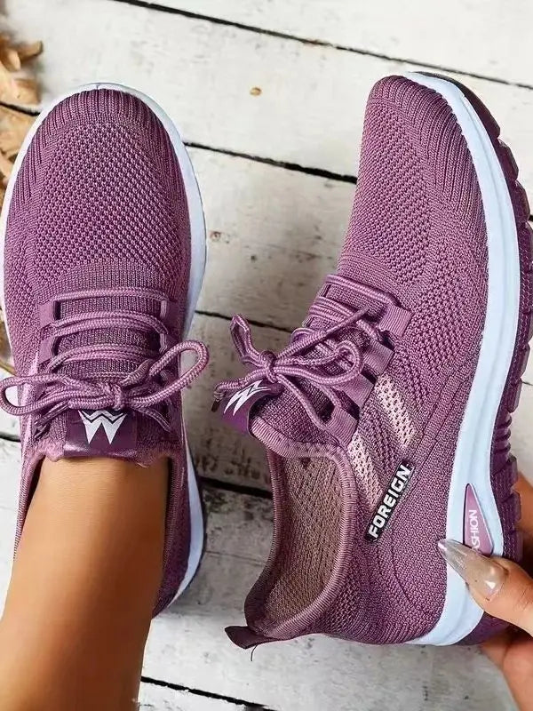 Purple running shoes with white soles on a wooden floor