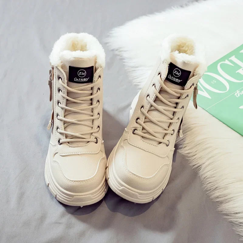 Pair of beige winter boots with white fur lining on a light gray surface.