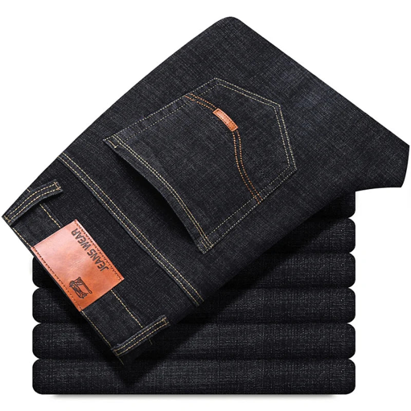Stack of folded dark blue jeans with a brand label on a white background