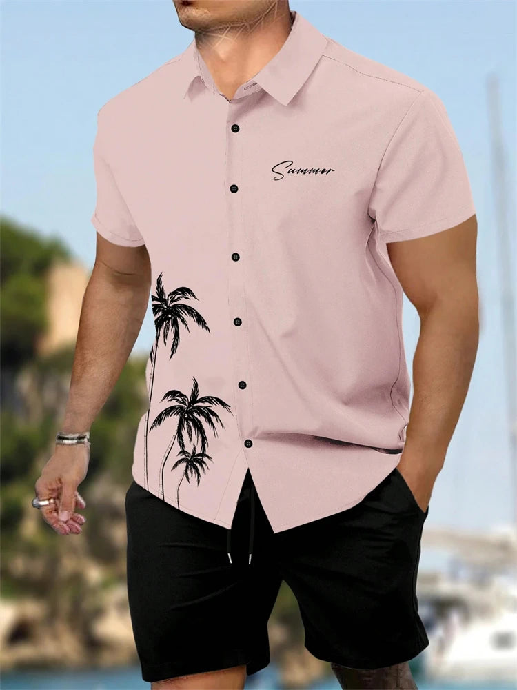 Man wearing a pink shirt with palm tree design and black shorts, standing outdoors.